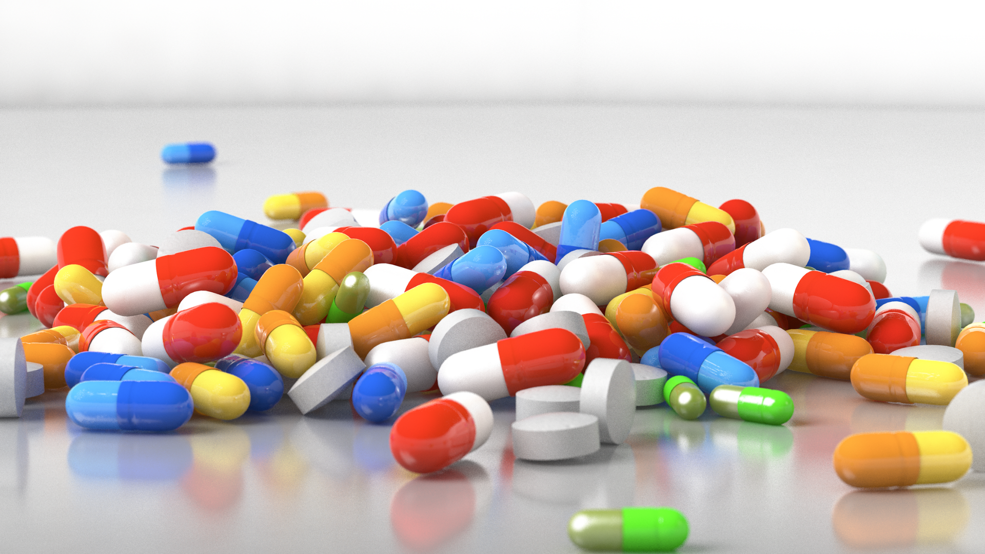 A colorful pile of vitamin capsules and tablets scattered across a white surface