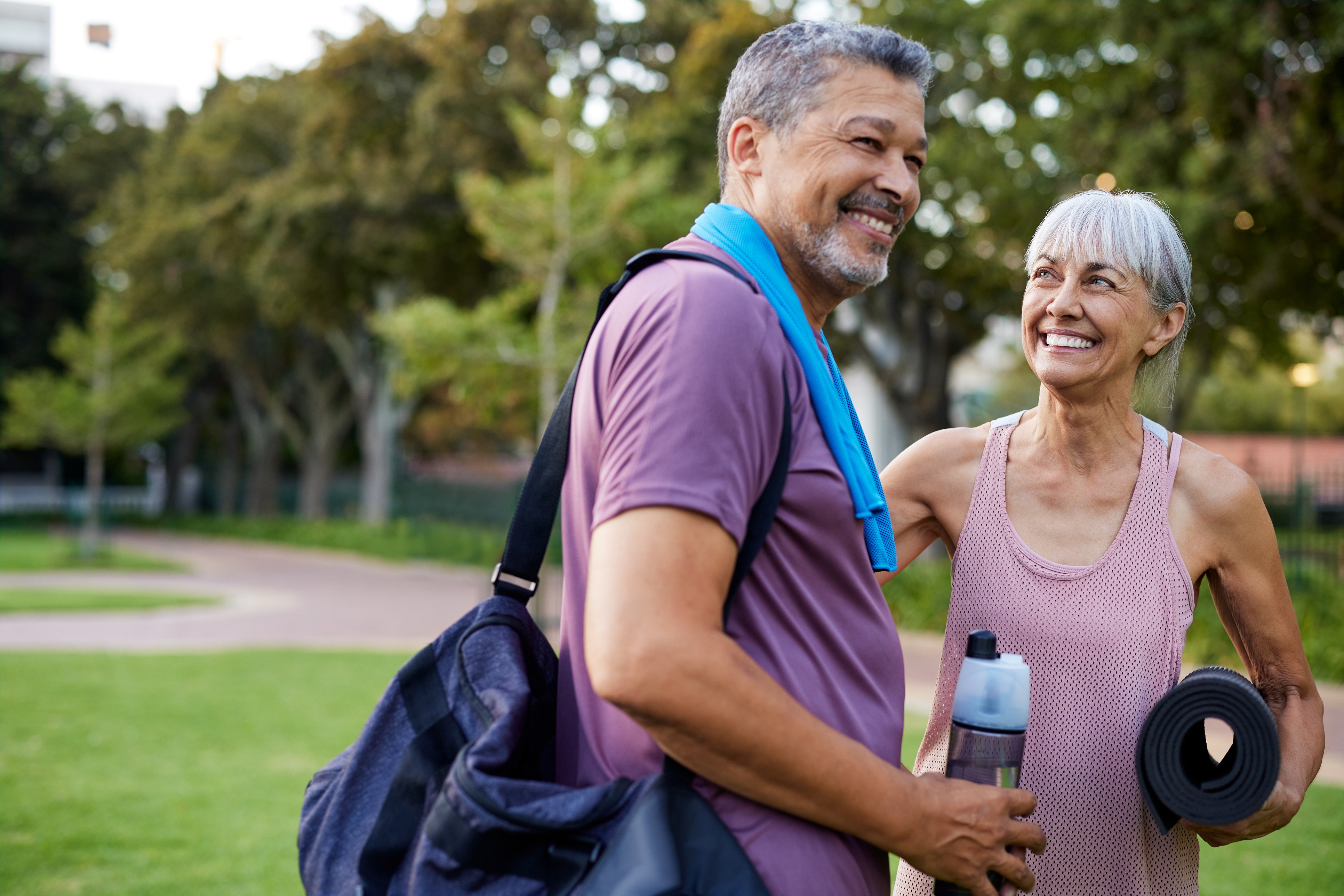 An active, smiling older couple with gym gear outdoors, energized after a workout